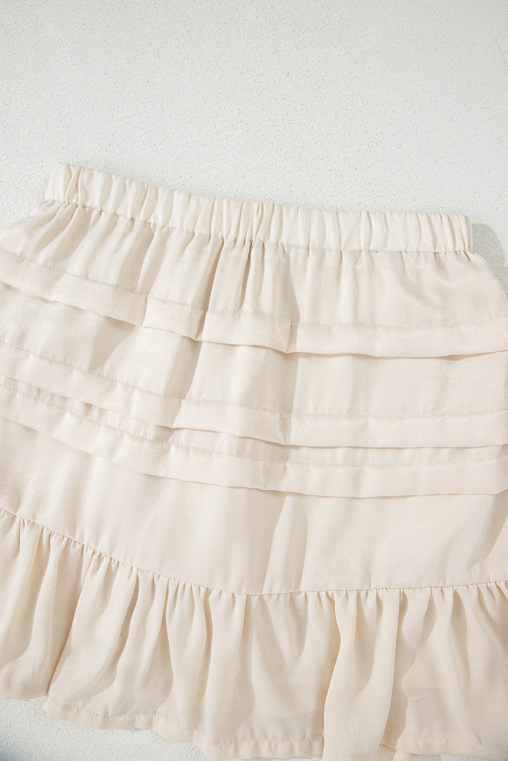 Beige tiered mini skirt with stacked ruffle bands and gathered waist