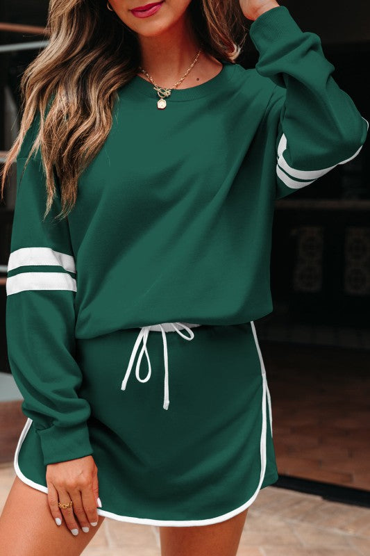 Green pullover with white striped cuff and green mini skirt with drawstring ties