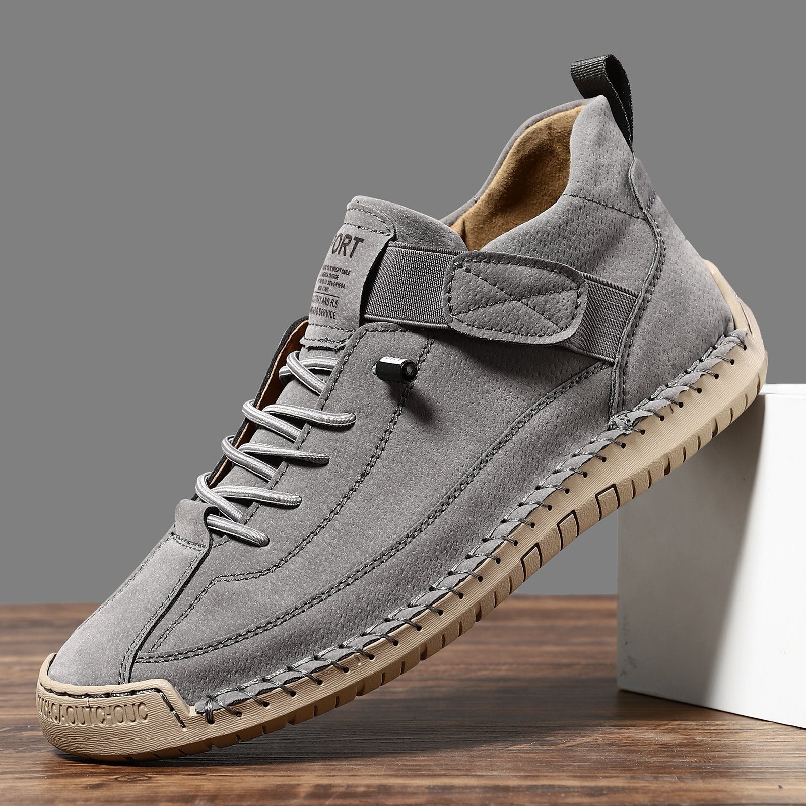 Casual leather boots in gray with lace-up front, side strap, and tan-textured tread sole.