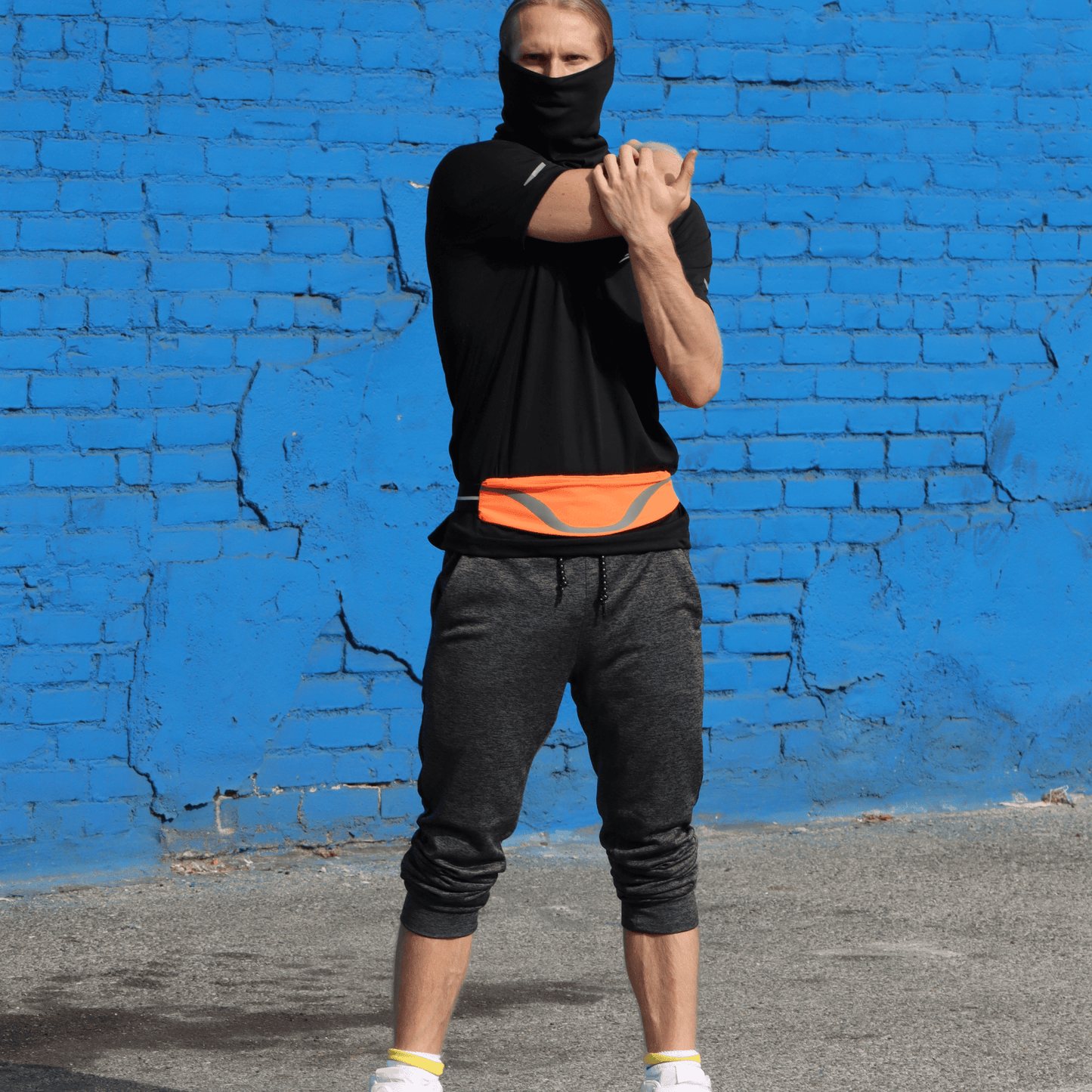 Water-resistant waist pack running belt with orange reflective stripe worn by runner.