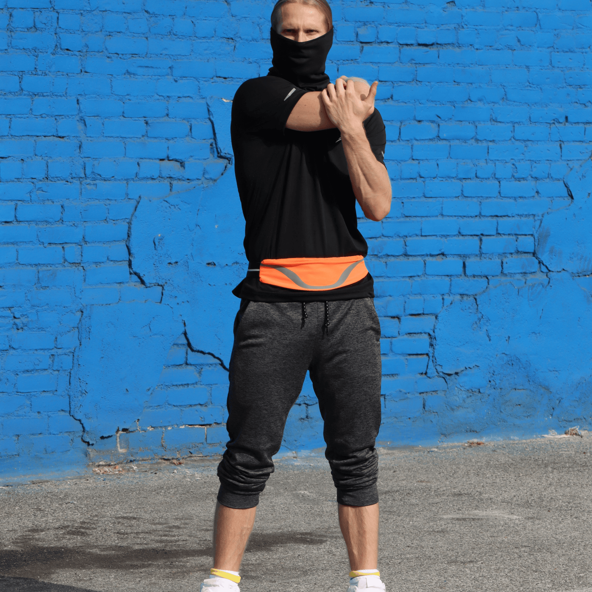 Water-resistant waist pack running belt with orange reflective stripe worn by runner.