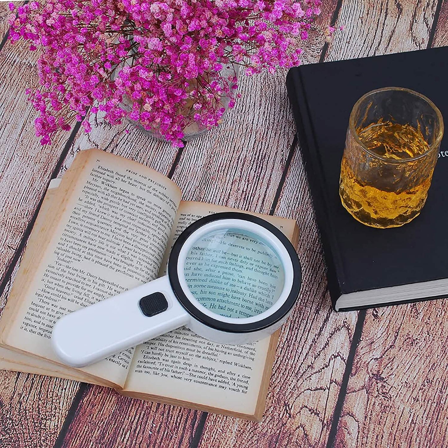 Handheld magnifying glass with 12 LEDs, white handle and black-rim lens on open pages