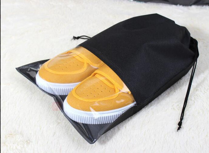 Black drawstring shoe storage bag with clear side, holding yellow and white shoes.
