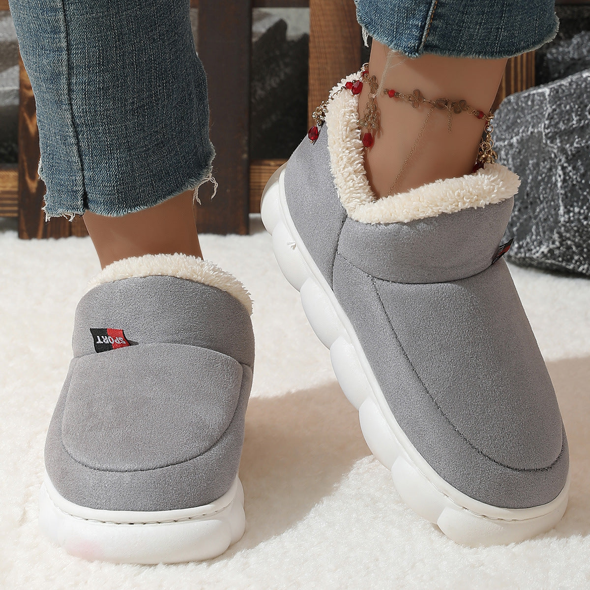 Grey plush house shoes with fuzzy strap and thick white sole, back view
