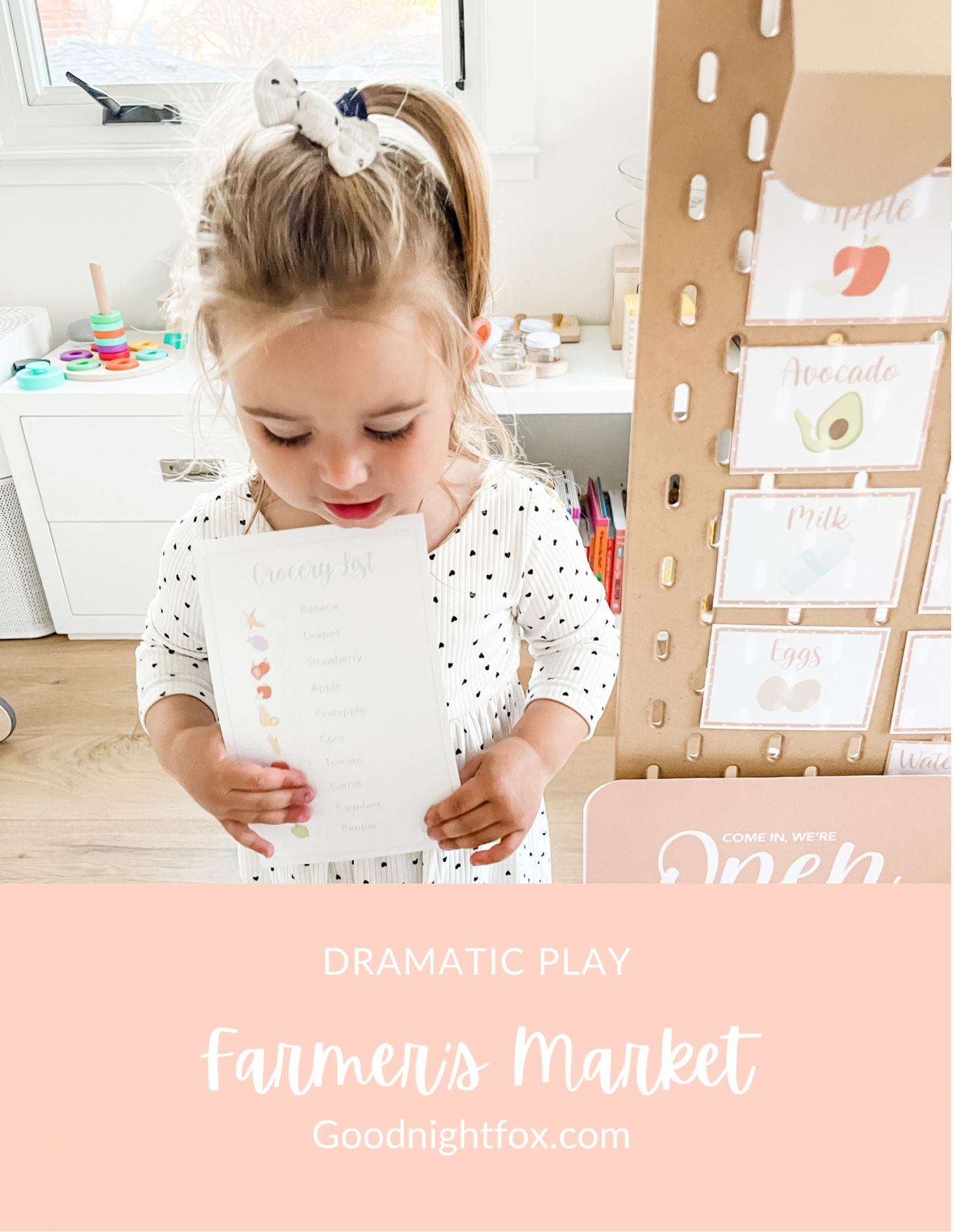 Child holding market cards near open play sign and produce card board