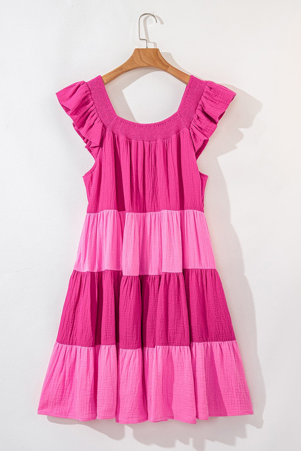 Pink tiered mini dress front view on a hanger with flutter cap sleeves