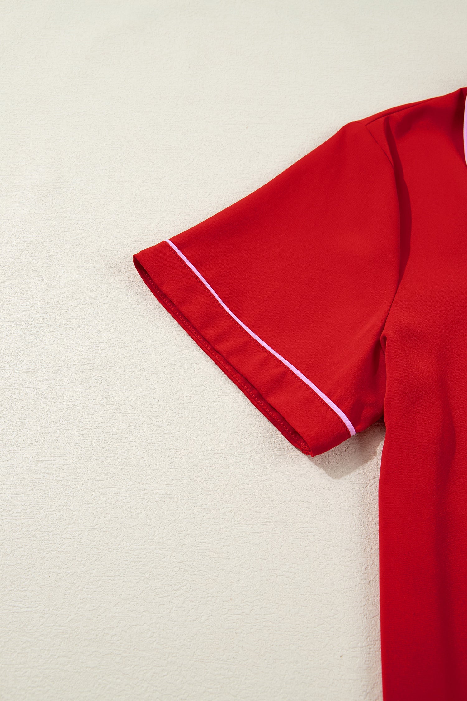 Red pajama top sleeve with white piping along the cuff