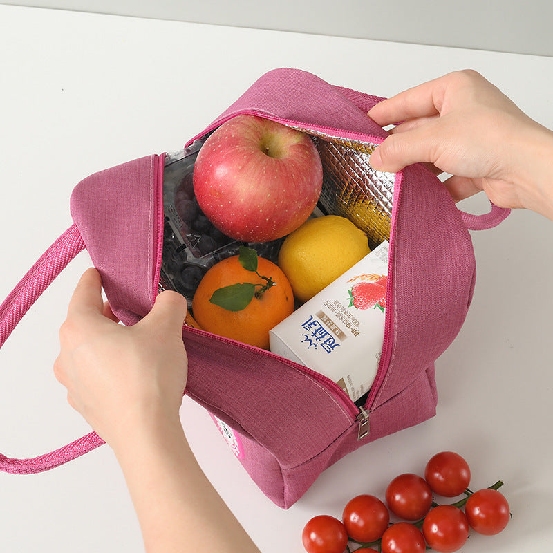 Pink insulated lunch bag with open top holding apples, oranges, and packaged food items.
