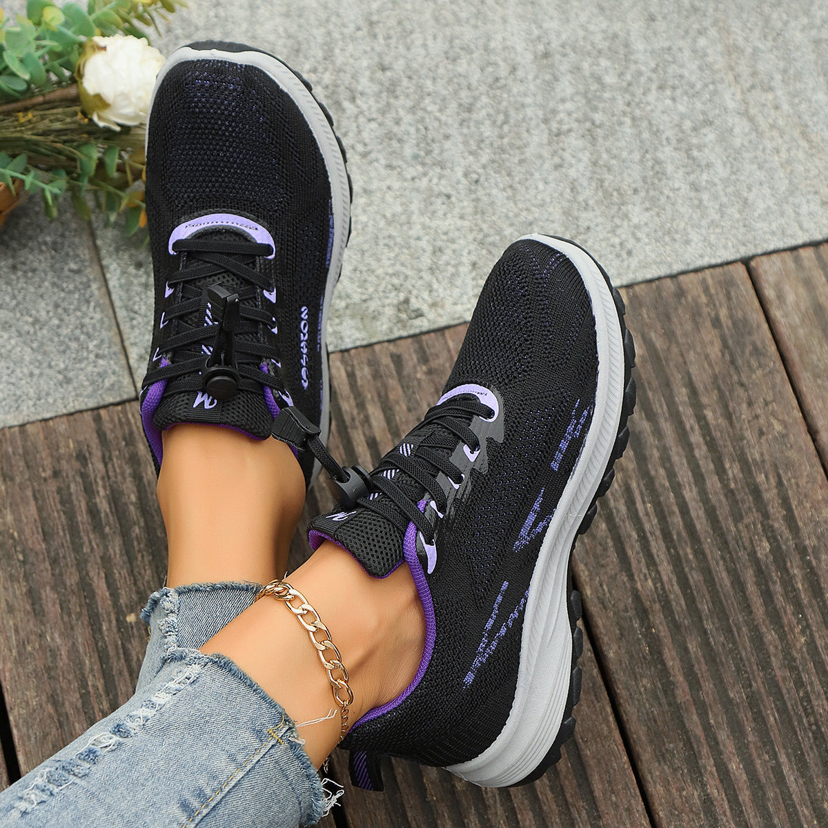 Black knit lace-up shoes with purple accents and white cushioned sole