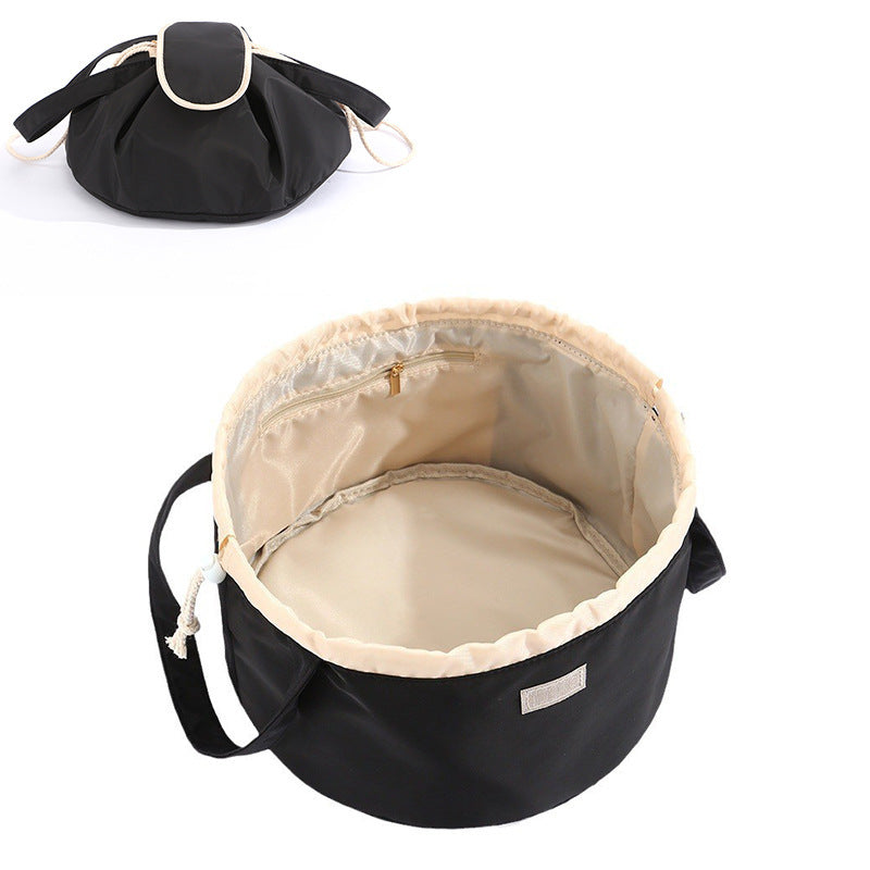 Black barrel drawstring makeup bag with top zipper and adjustable shoulder strap