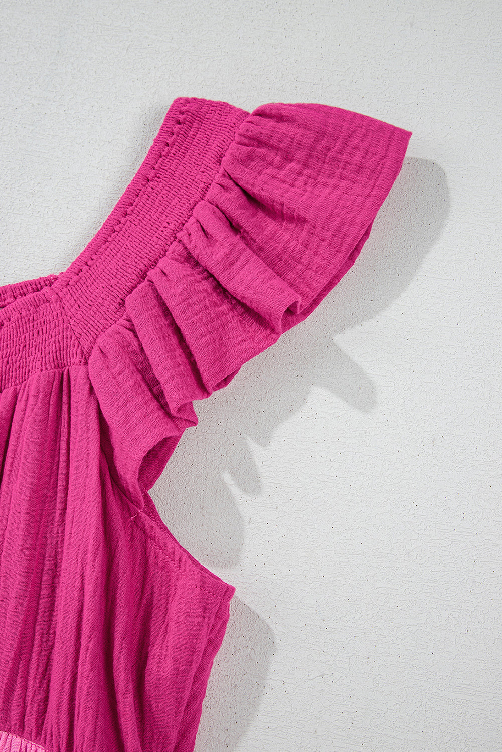 Close-up of pink tiered mini dress flutter sleeve and layered tier seam