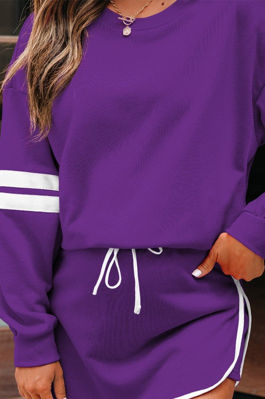 Purple pullover with white stripe cuff, paired with mini skirt and white drawstring.
