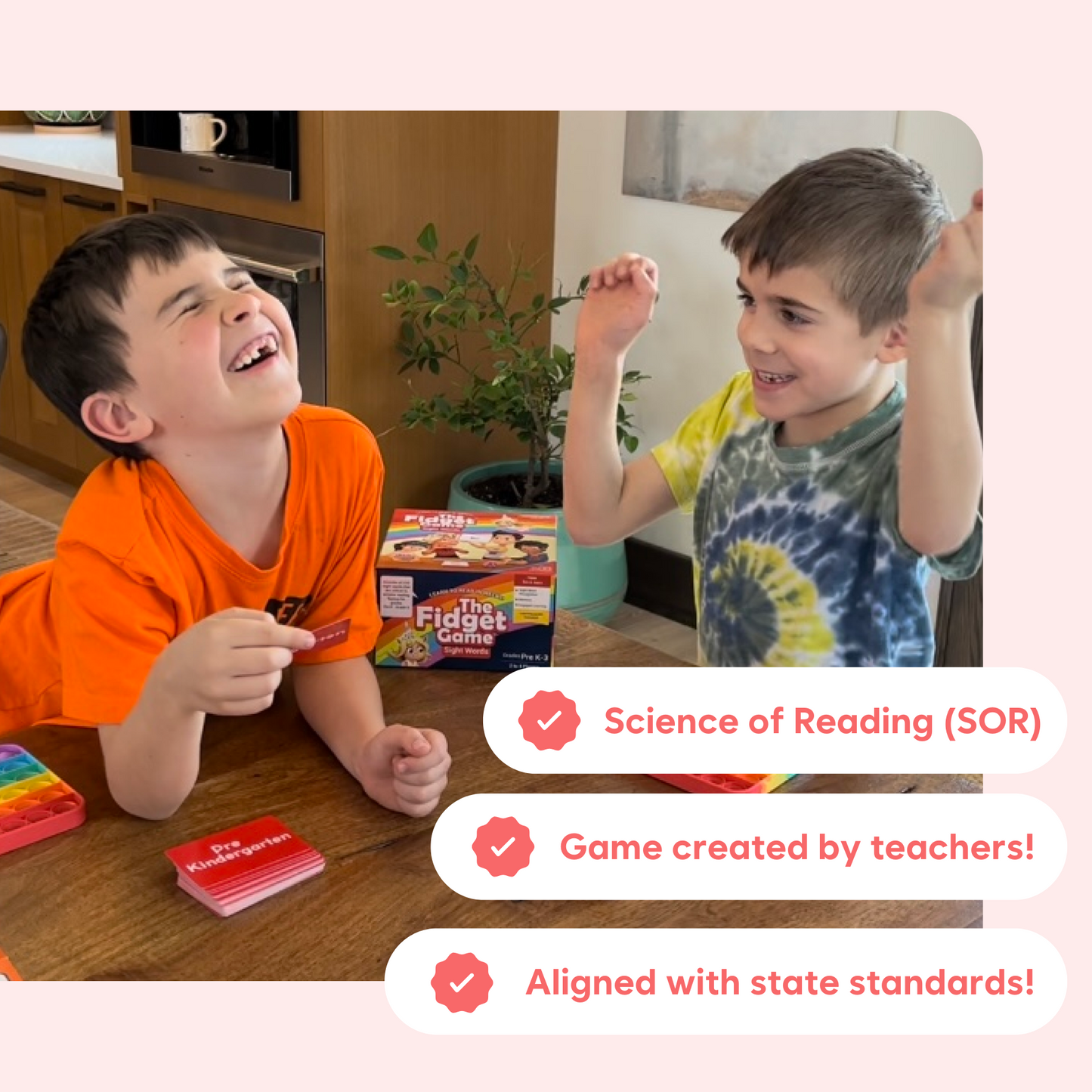 Two kids playing a reading board game with the fidget mat and word cards on table