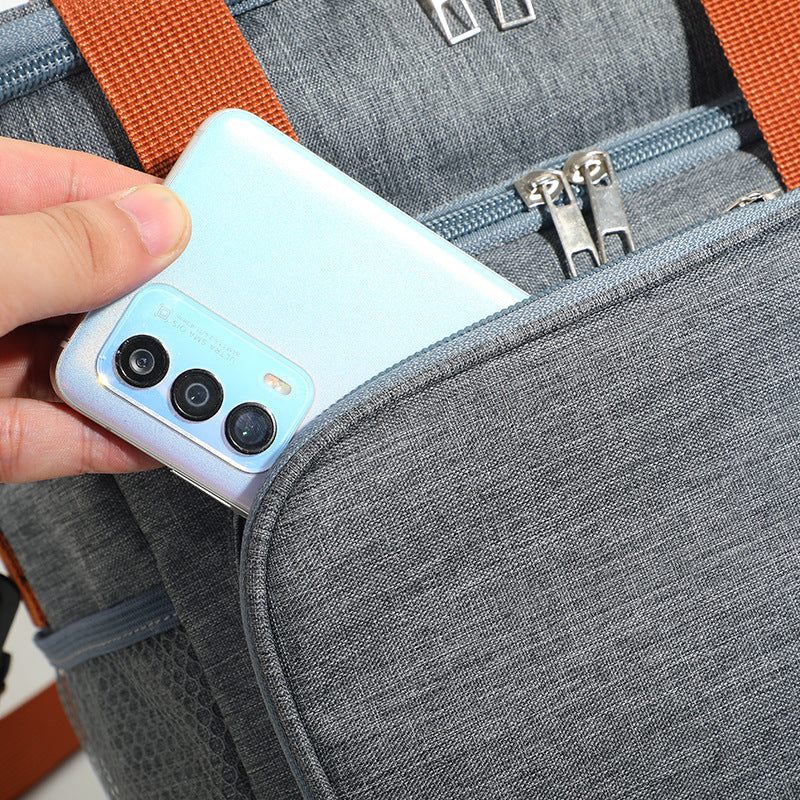 Gray insulated lunch bag cooler crossbody with front zipper pocket holding a smartphone