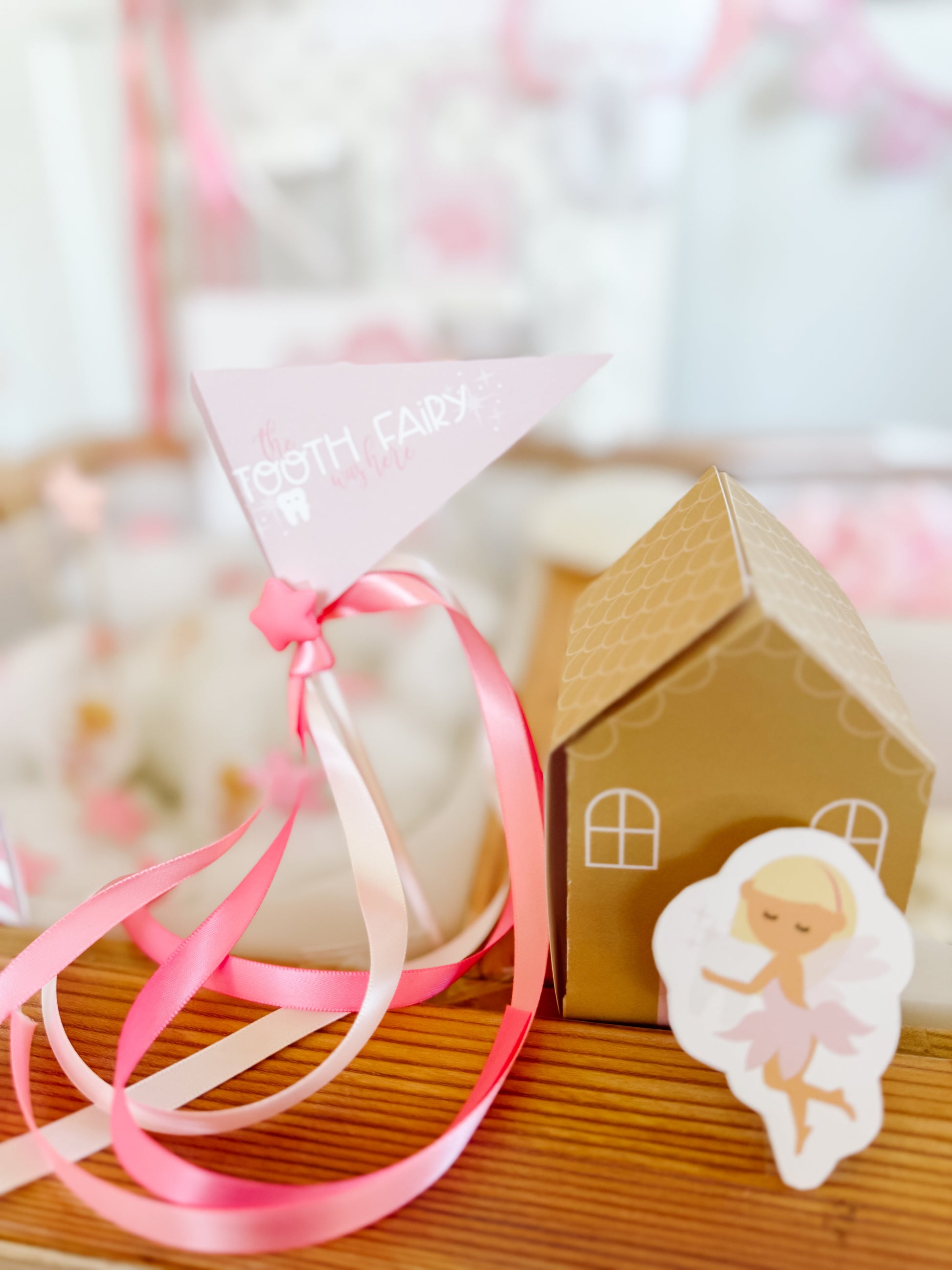 Pink ribbon bag and small cardboard tooth fairy house with angel cutout, side view