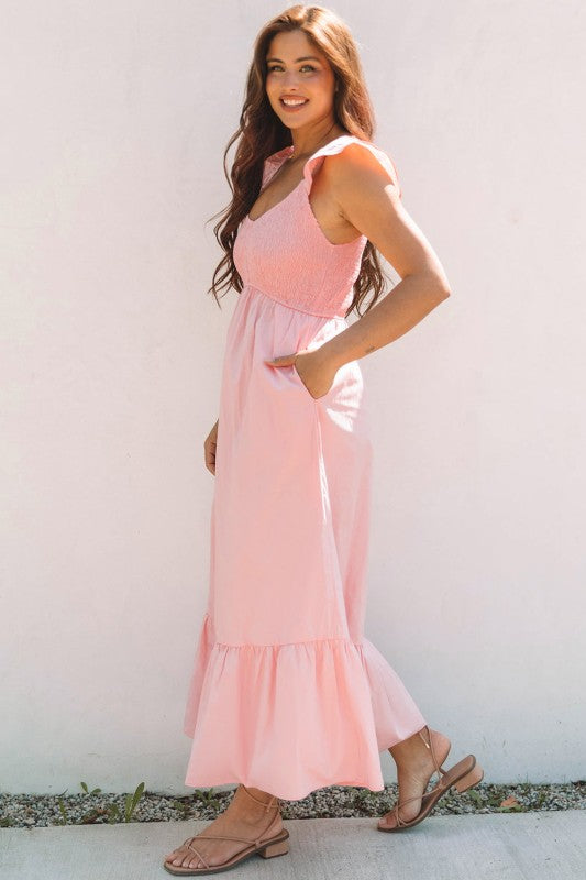 Apricot pink maxi dress angled view with smocked bodice, flutter sleeves, tiered skirt