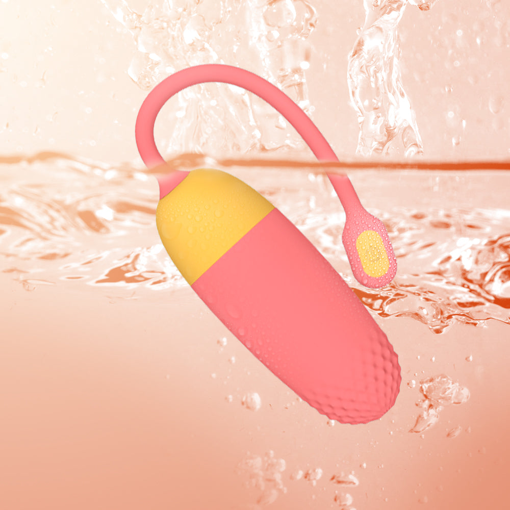 Pink and yellow loop-handled silicone massager in water with textured base