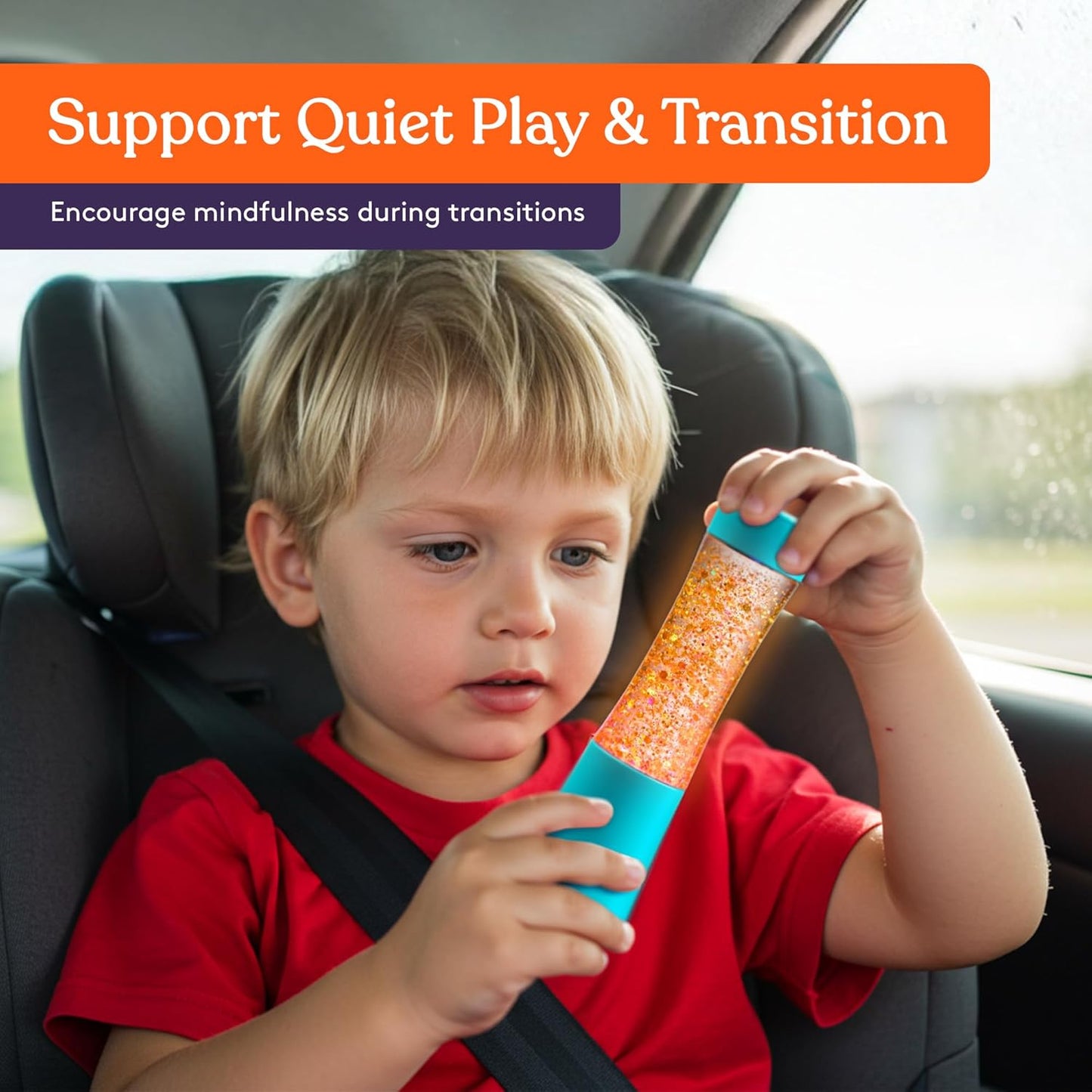 Child holding an orange glitter sensory tube with blue base and glowing contents