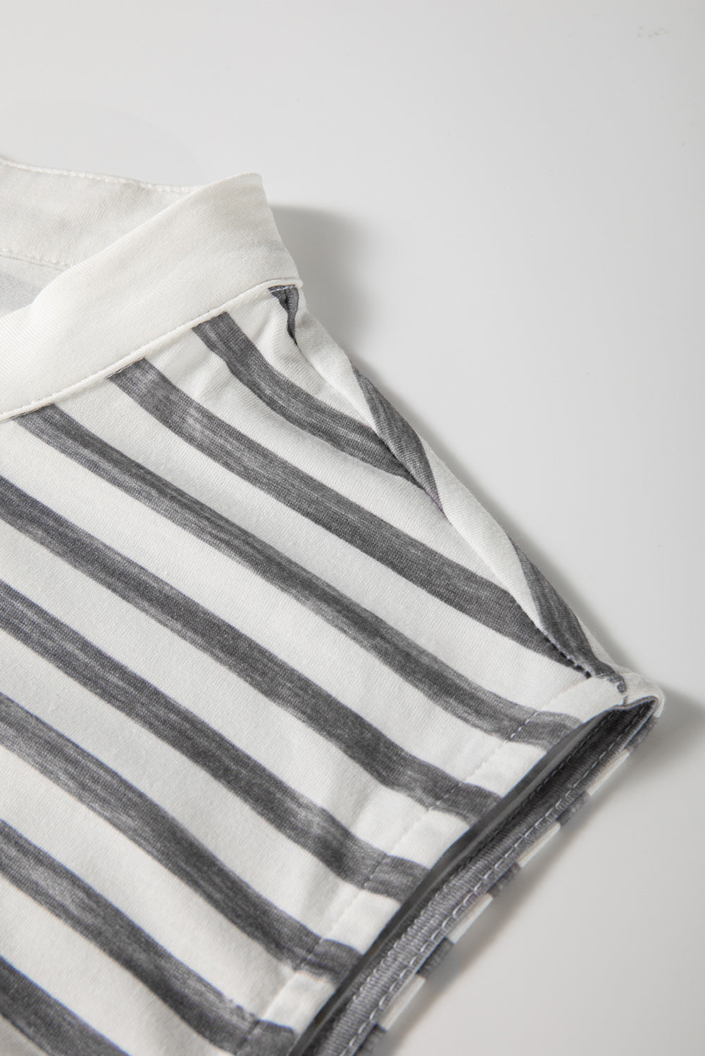 Sleeveless jumpsuit showing gray stripe inner facing and seam detail near neckline
