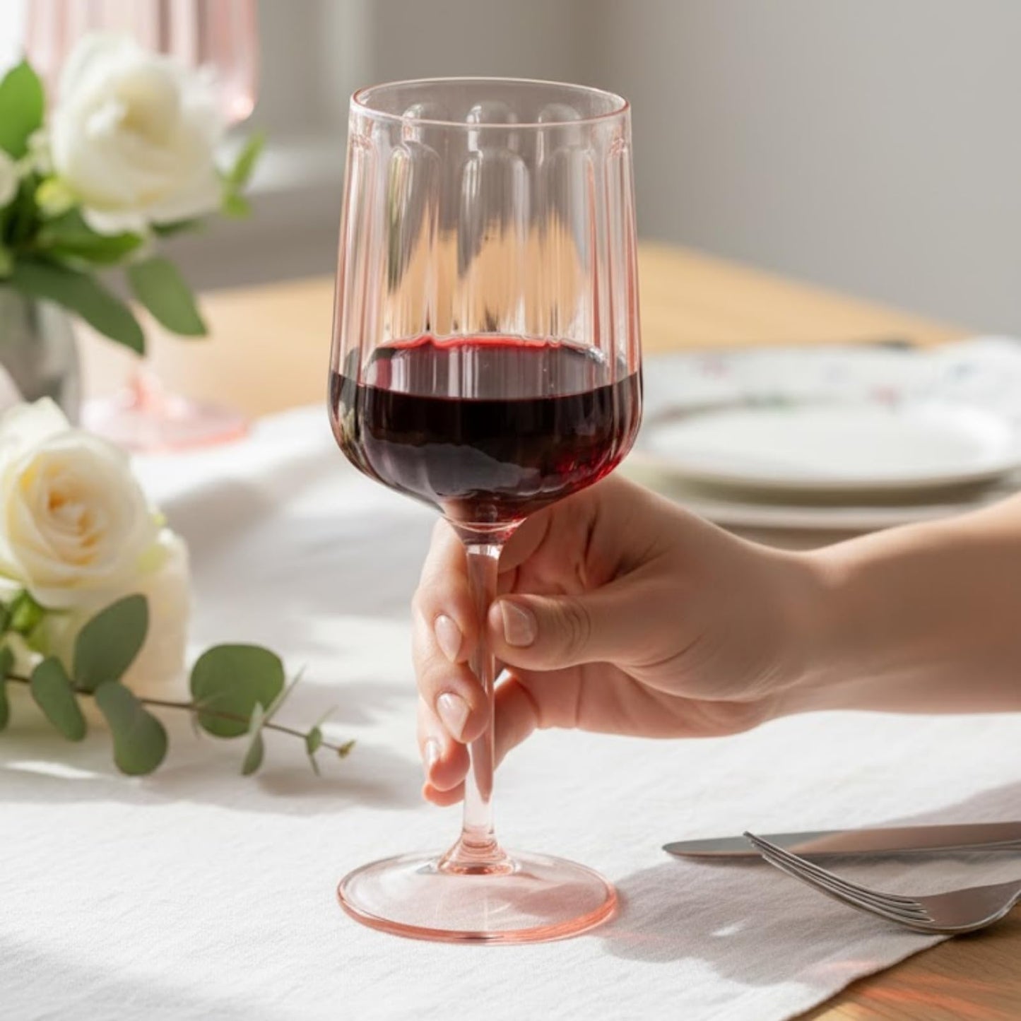 Pink acrylic stemmed goblet with ribbed cup and flared round base in hand