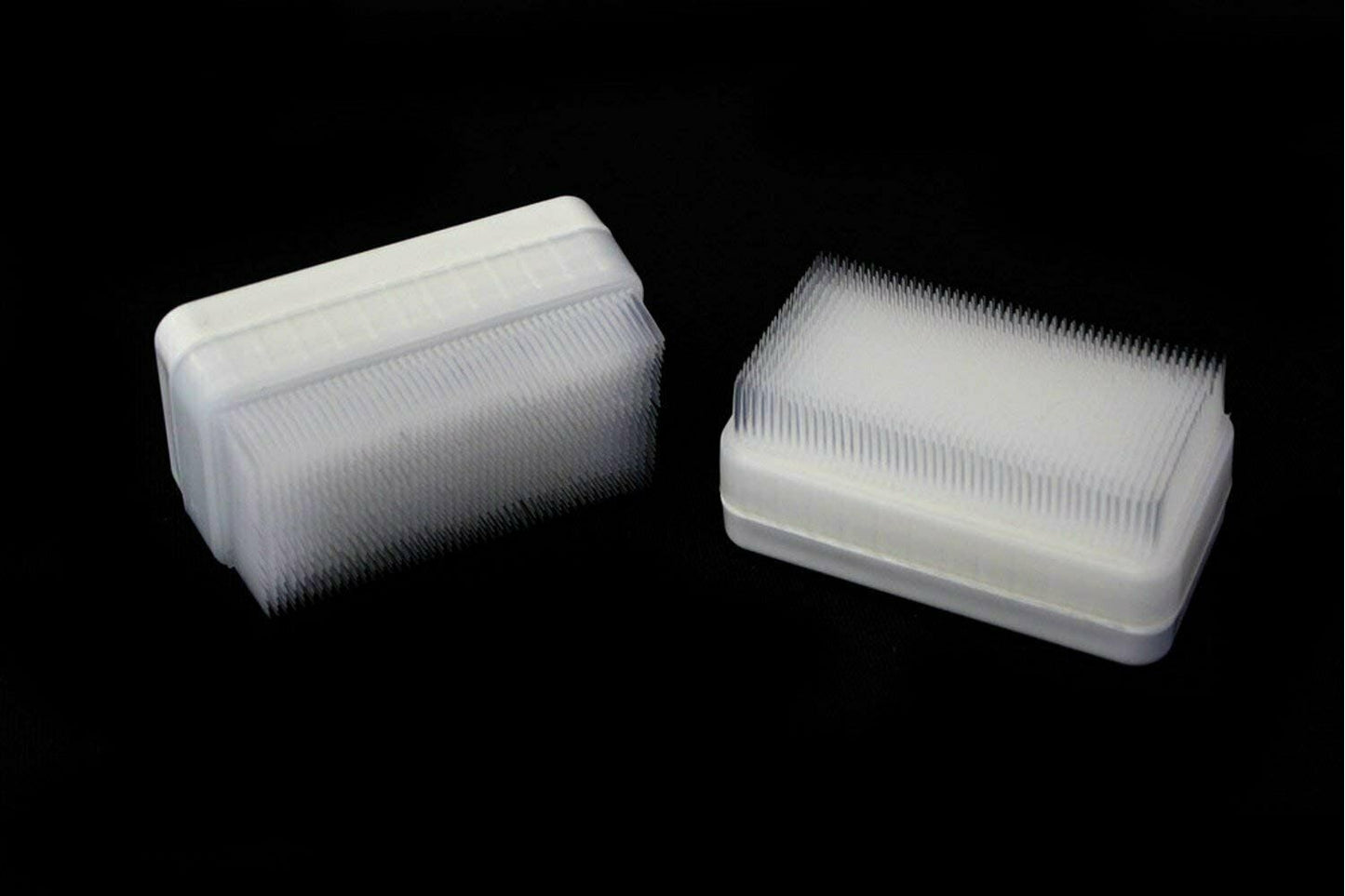 Two compact therapressure brushes with white bristles on clear plastic housings