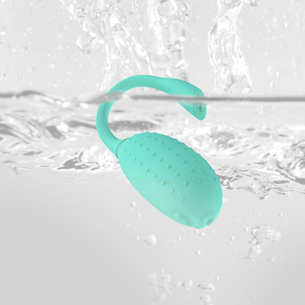 Light teal silicone massager with textured surface and curved handle, in water.