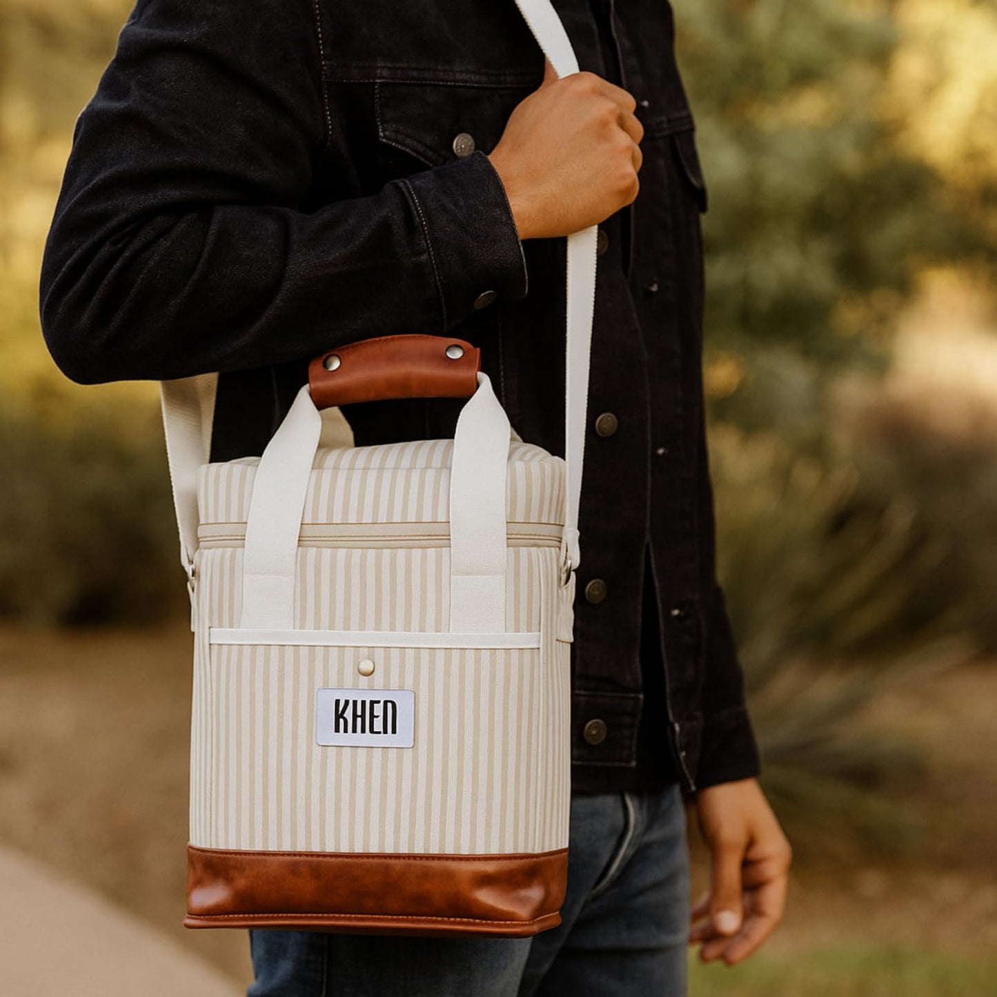 2-bottle wine tote cooler bag with white carry straps, cream striped fabric, brown leather base