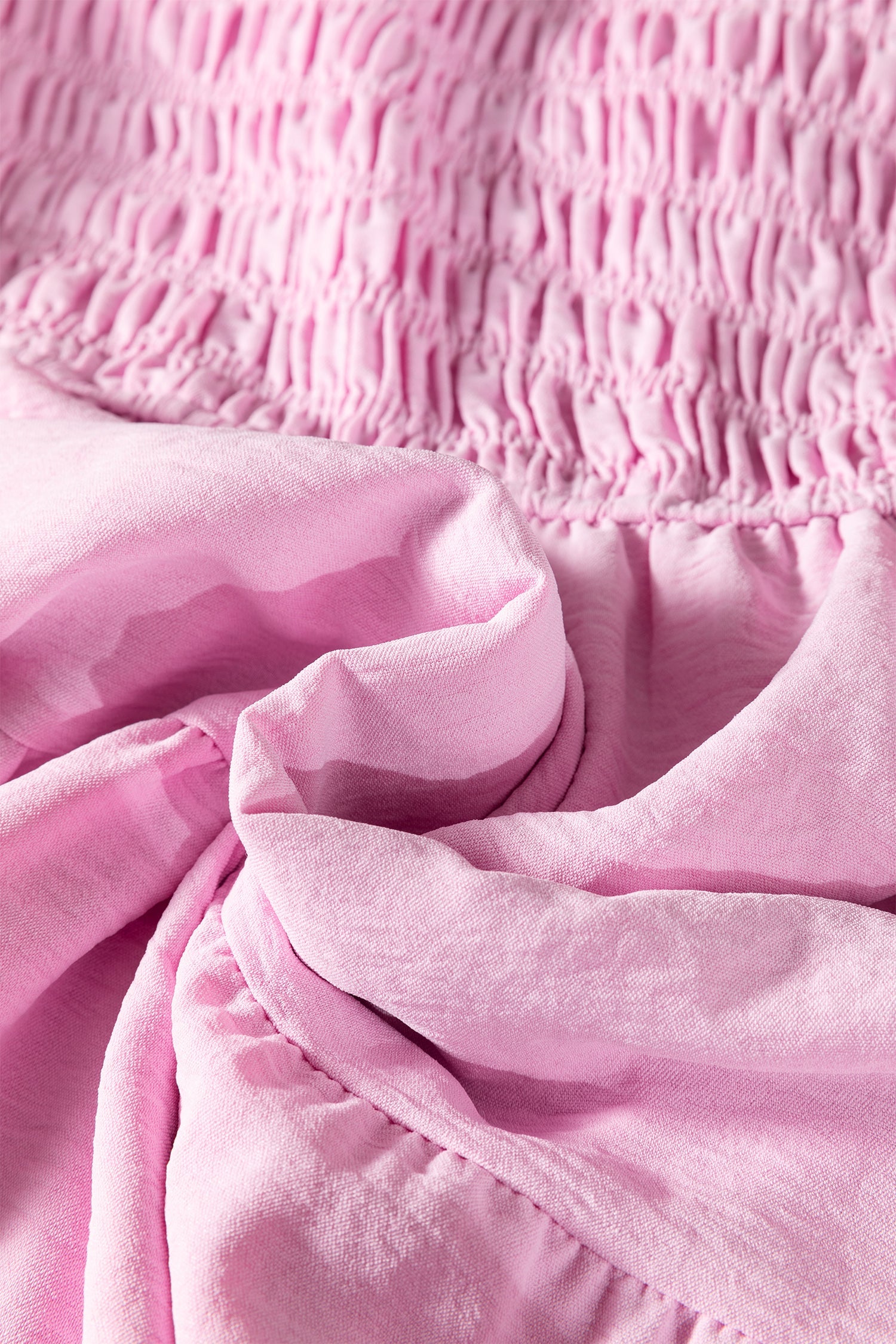 Pink tiered midi dress close-up of smocked waist and ruffled skirt layers