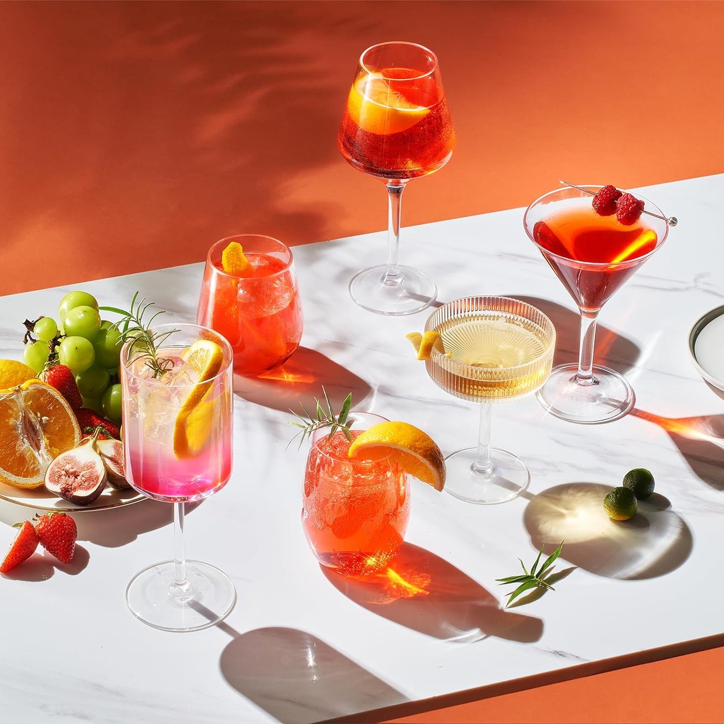 Stemmed wine glasses with clear goblets filled with yellow, red, and pink drinks
