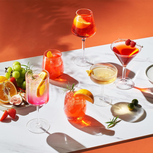 Stemmed wine glasses with clear goblets filled with yellow, red, and pink drinks