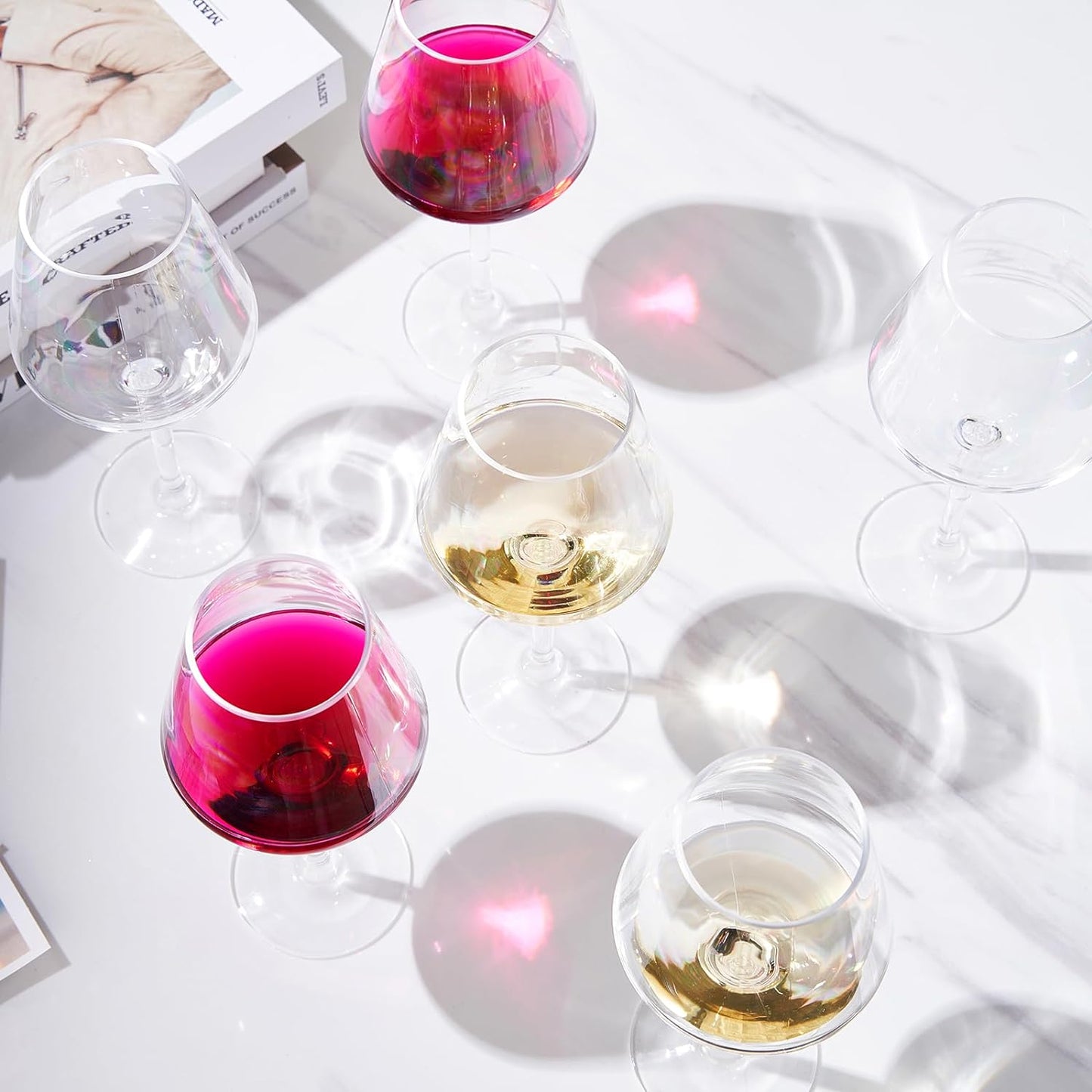 Assorted stemmed wine glasses with clear bowls filled with pink and golden drinks