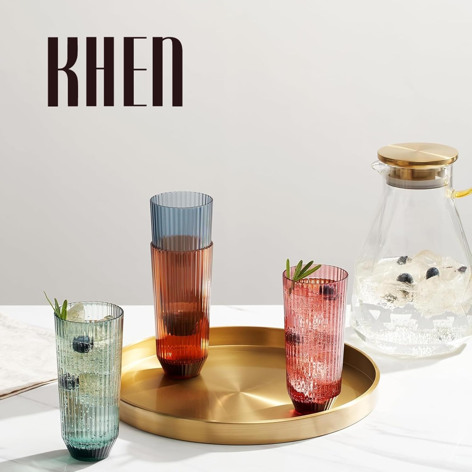 Set of four tall ribbed tumbler glasses on a tray in muted blue, green, red, and amber