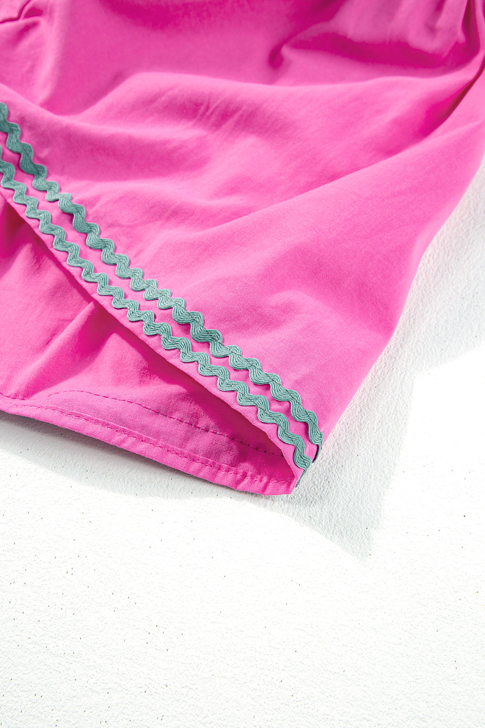 Hem detail on strawberry pink dress with contrasting zigzag trim and sewn ruffle edge