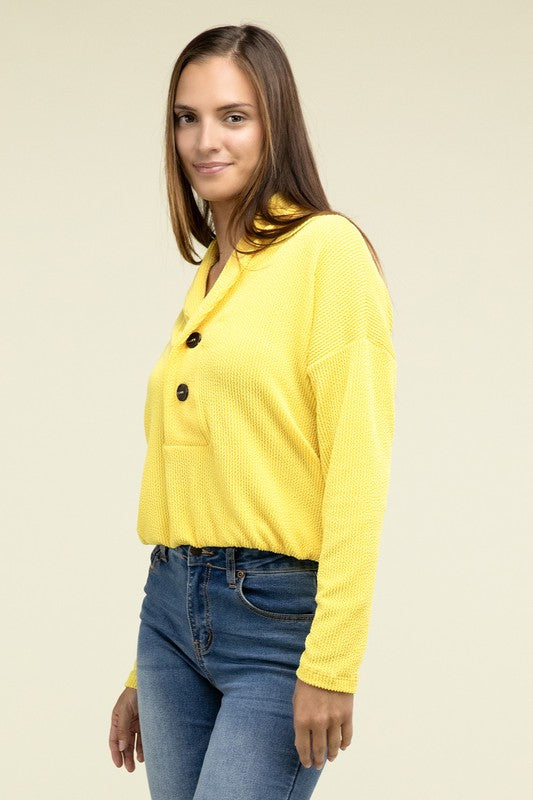 Yellow textured pullover top with V-neck, button closure, chest pocket, long sleeves