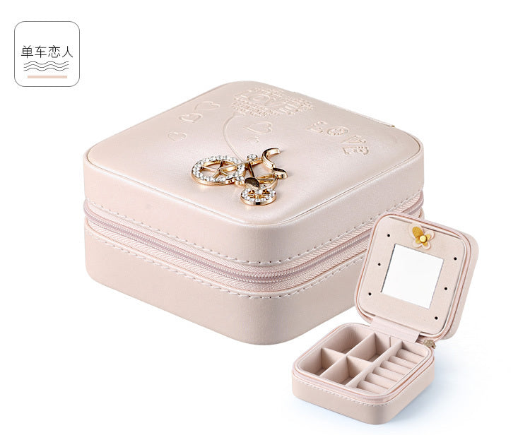 Beige jewelry organizer case with embossed top, hinged mirror, zipper, and ring compartments