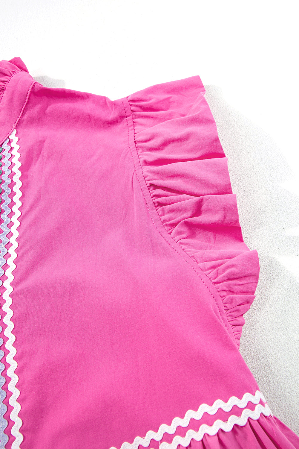 Side view of strawberry pink dress with back ruffle sleeve and zigzag trim along hem