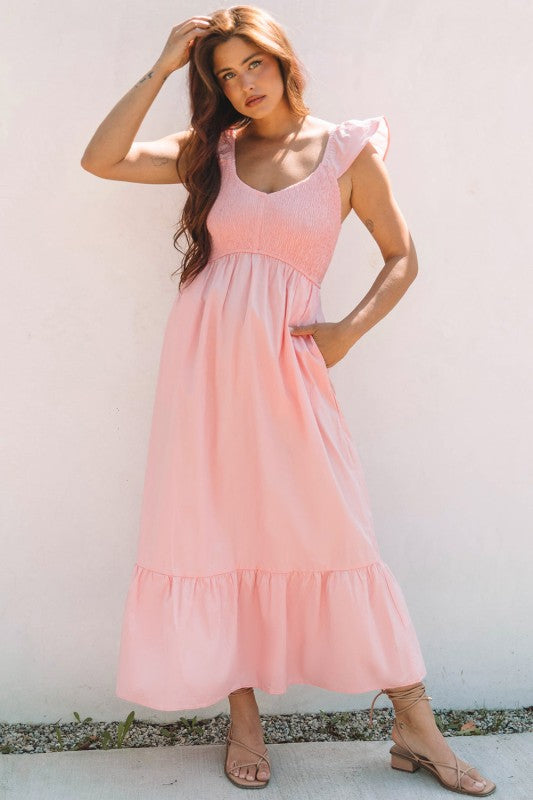 Apricot pink maxi dress front view with smocked bodice, flutter sleeves, and tiers