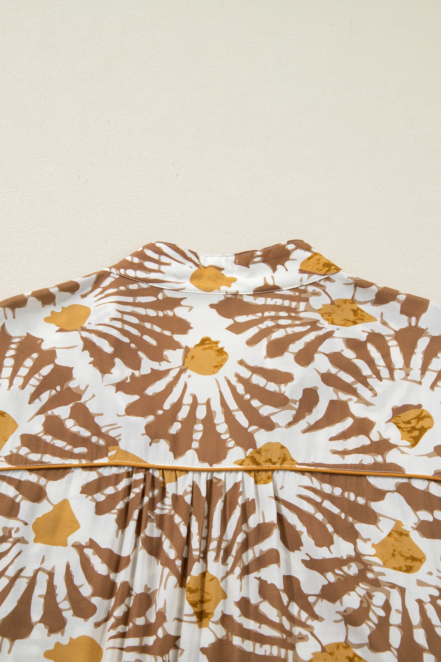 Loose long plus dress with gathered bodice and abstract brown-and-yellow print.