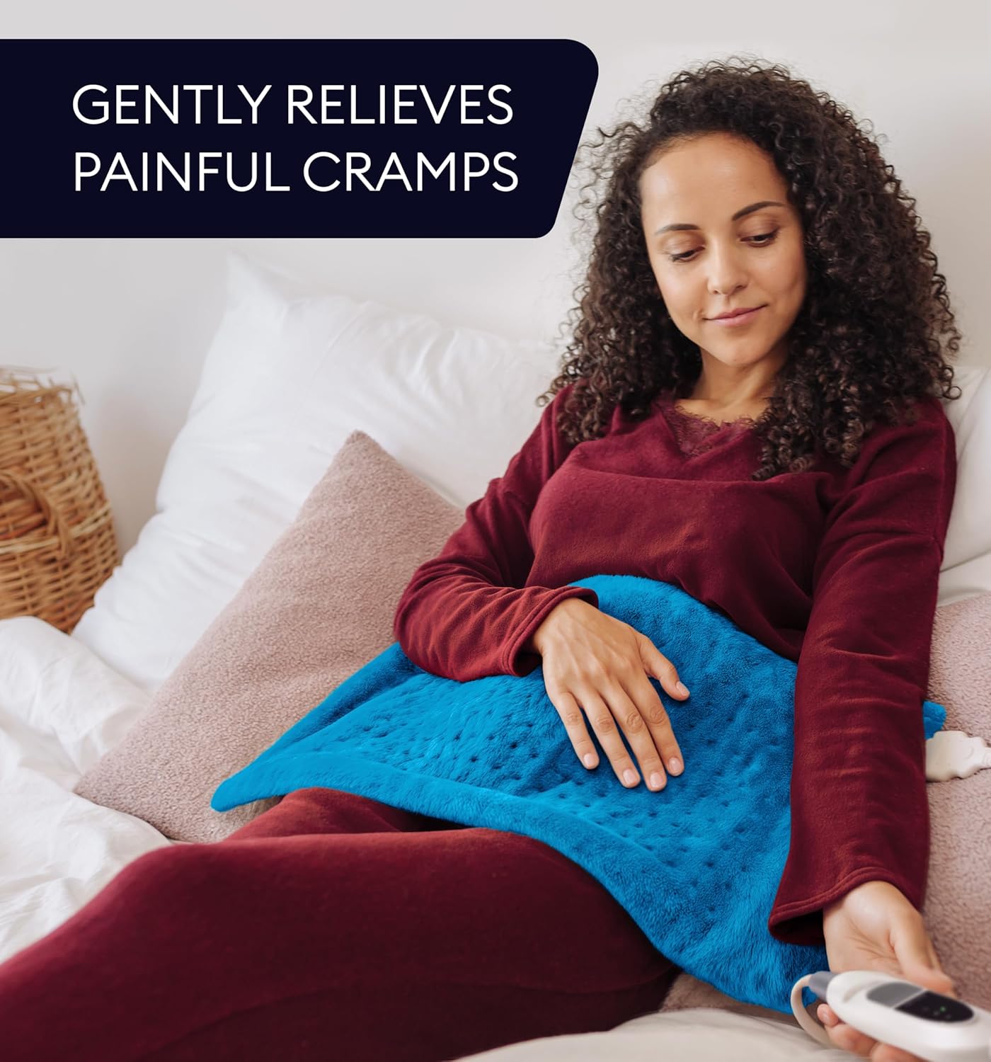 Aqua blue heating pad over legs on a couch with a handheld remote controller