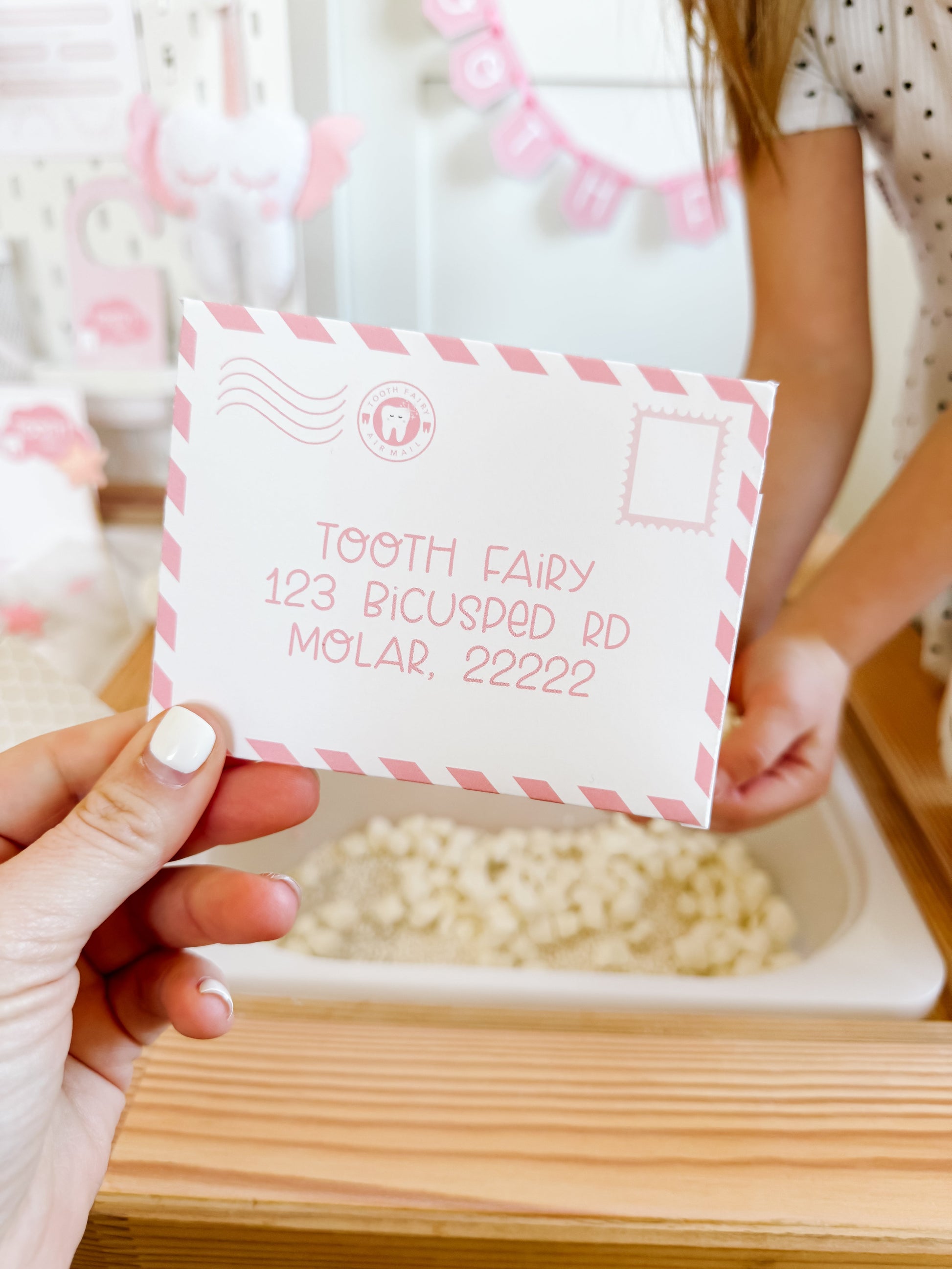 Tooth fairy note card with tooth icon and sample text, held in a hand