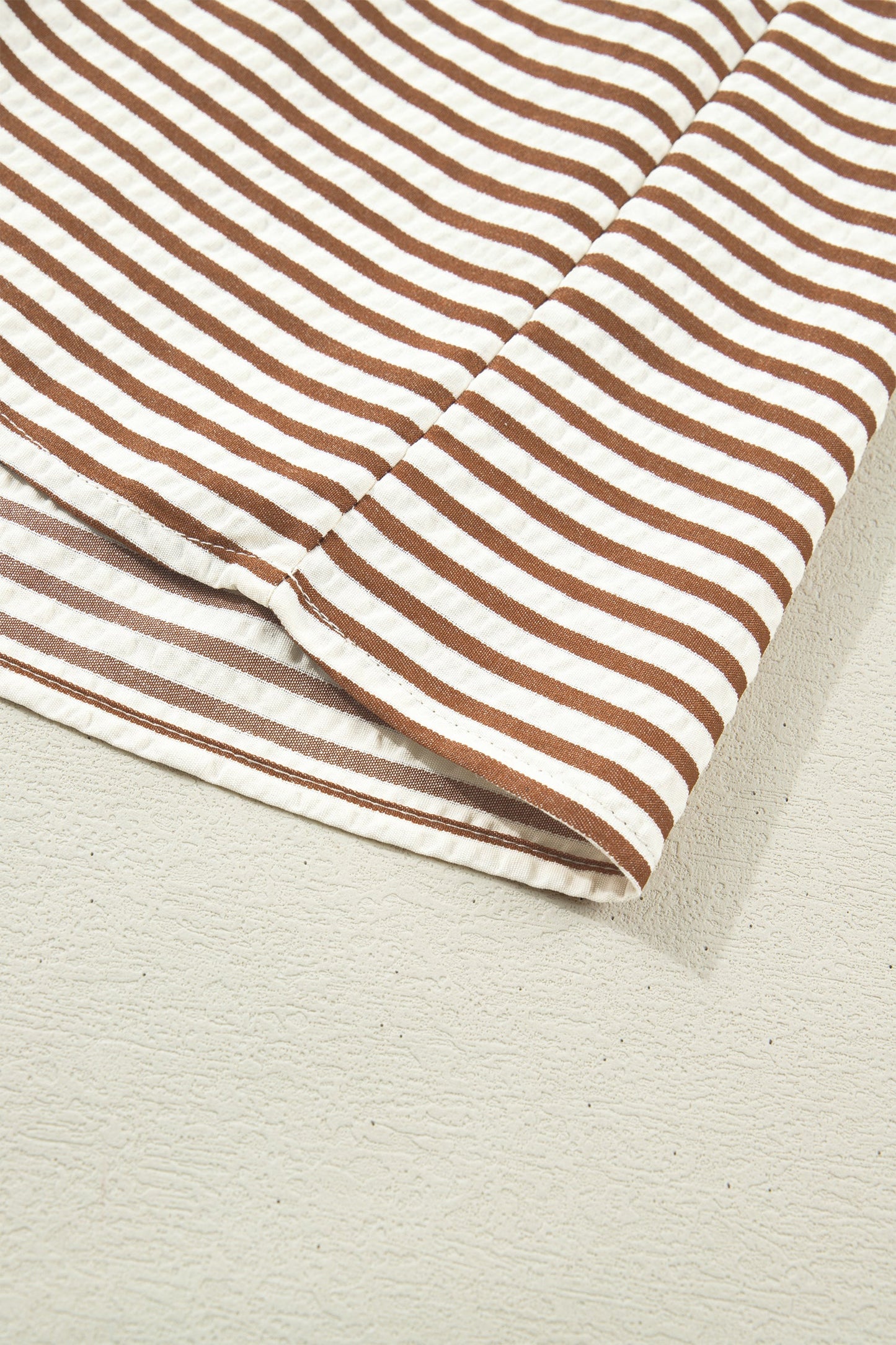 Brown-and-cream striped dress fabric with stitched hem edge