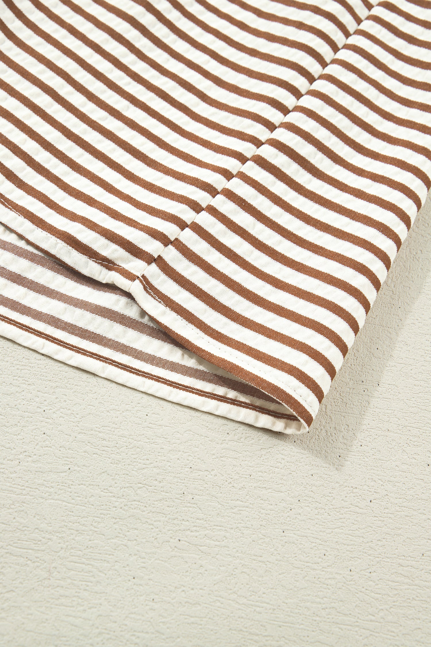 Brown-and-cream striped dress fabric with stitched hem edge