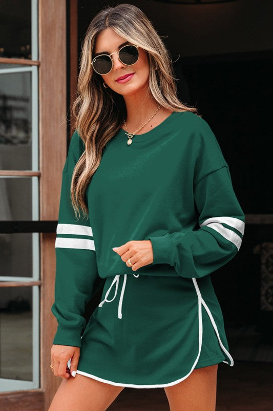 Green pullover with white stripe sleeves and green mini skirt with drawstring trim