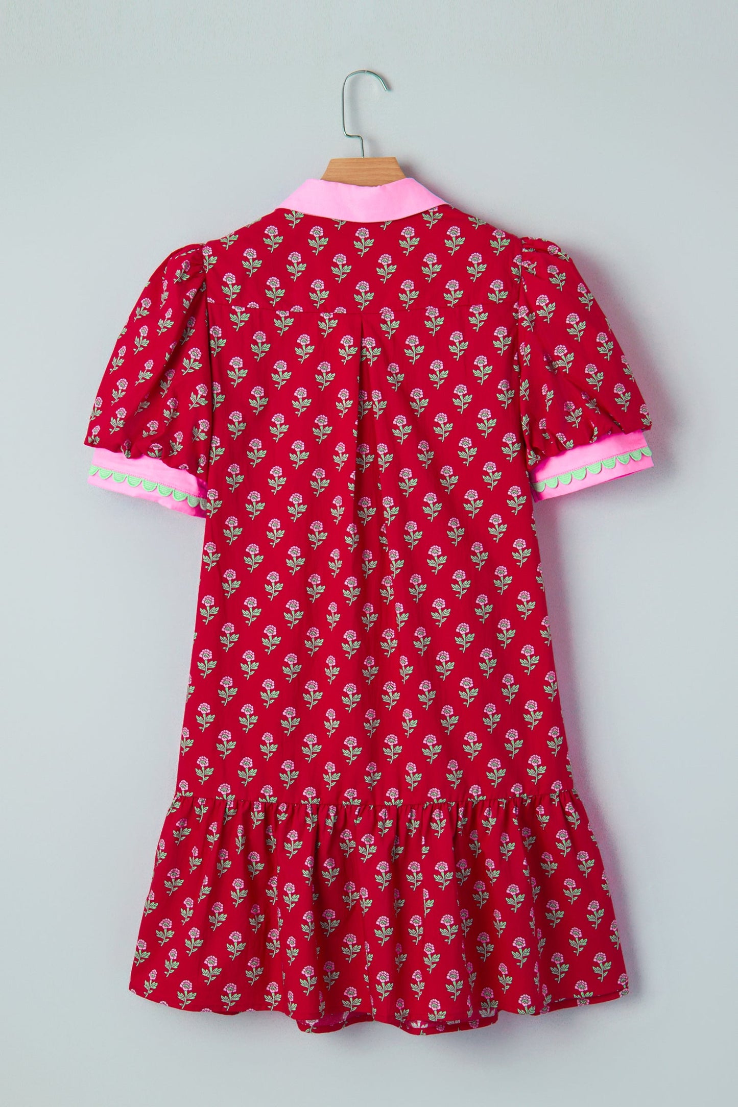 Back view of red mini dress on a hanger with pink-trim sleeves and gathered hem.