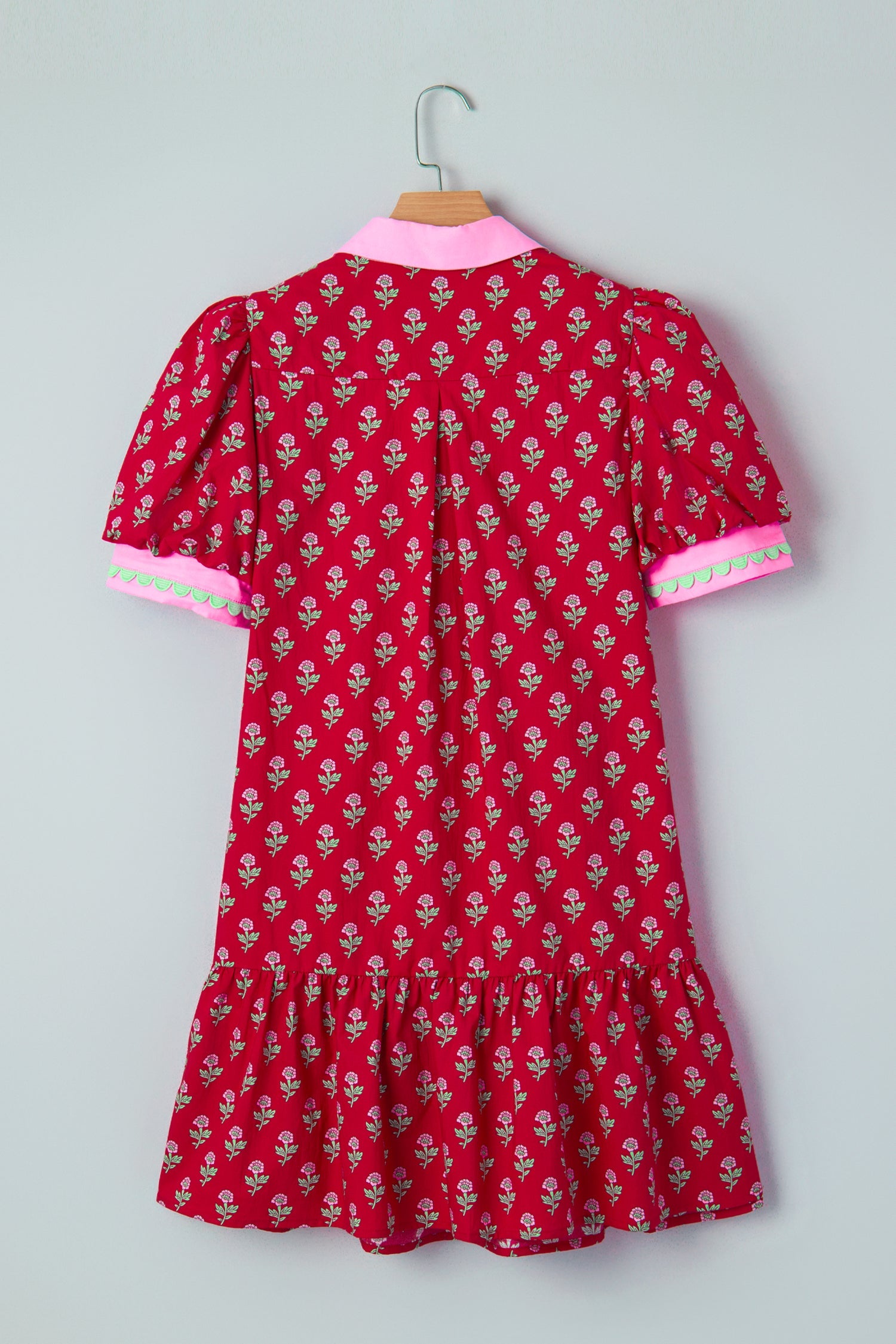 Back view of red mini dress on a hanger with pink-trim sleeves and gathered hem.