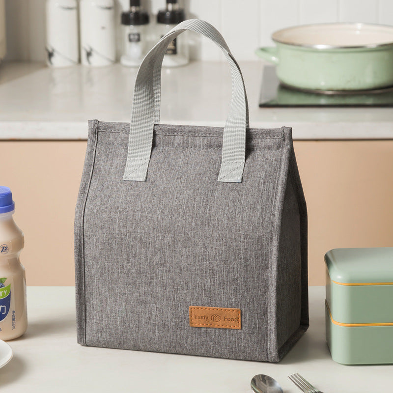 Dark gray insulated lunch bag with light gray handles and tan logo label patch