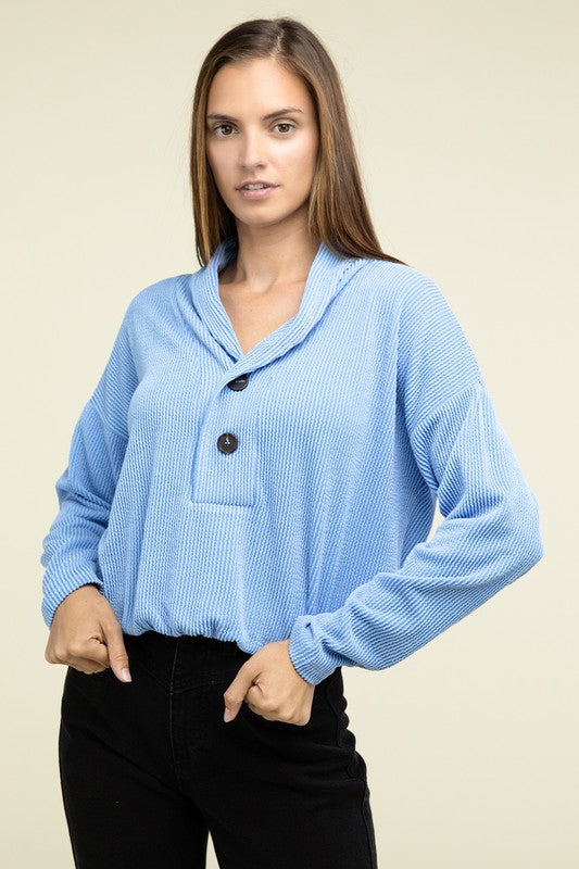 Light blue textured pullover top close-up with collared V-neck and two buttons