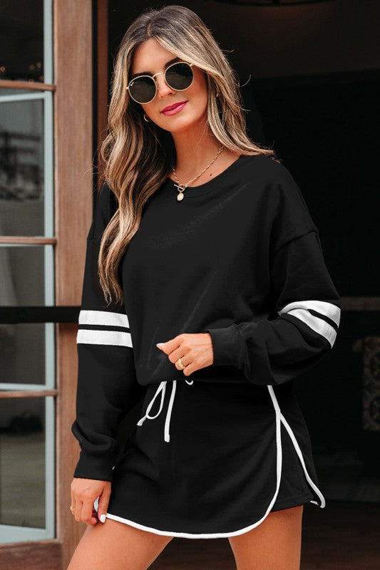 Black varsity stripe pullover and mini skirt set, side view with white-striped cuffs and drawstring.