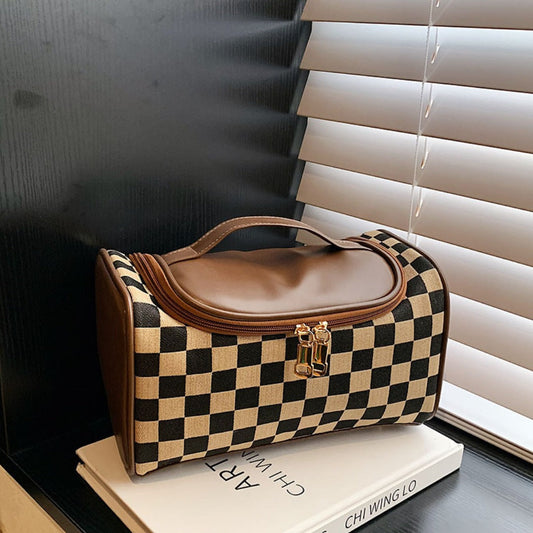 Plaid cosmetic bag in black and cream with brown zipper trim and top handle