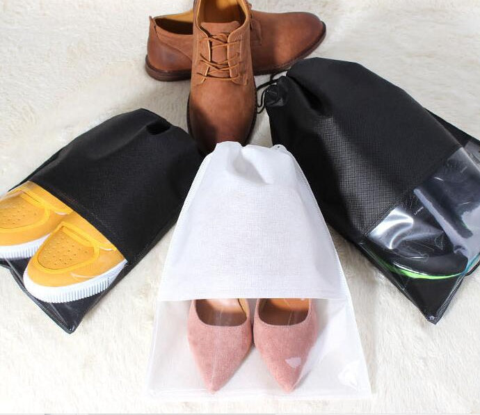White and black drawstring shoe bags holding pink, yellow, and brown shoes.